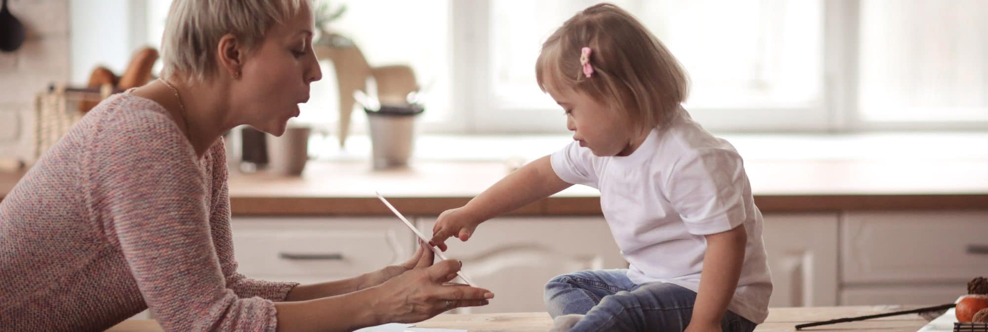 photo of woman helping a girl with down syndrome learn