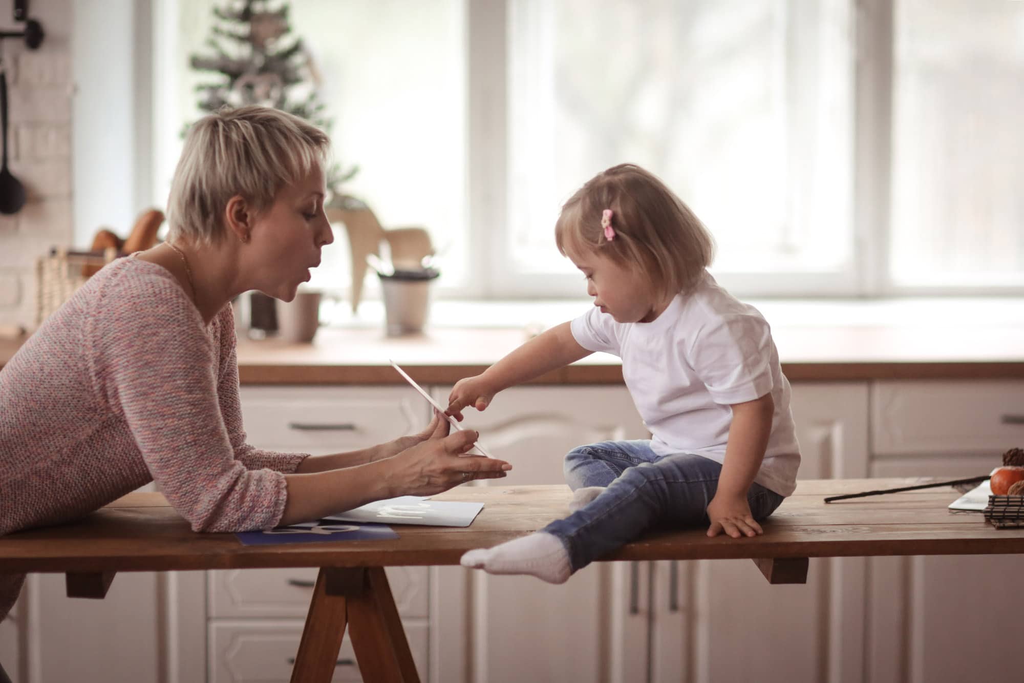 photo of woman helping a girl with down syndrome learn