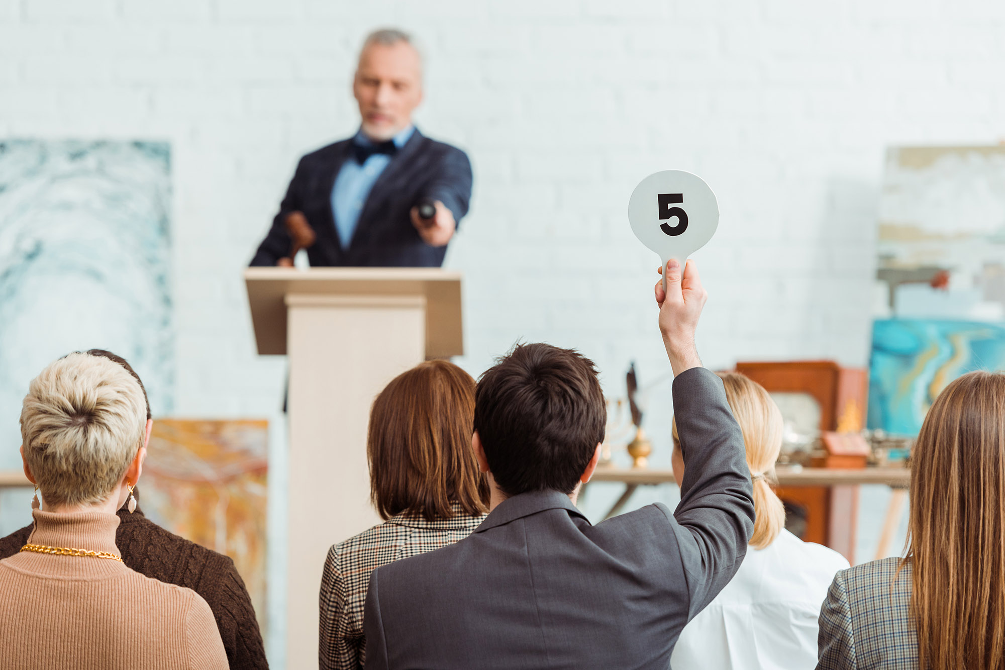 man holding up number at auction