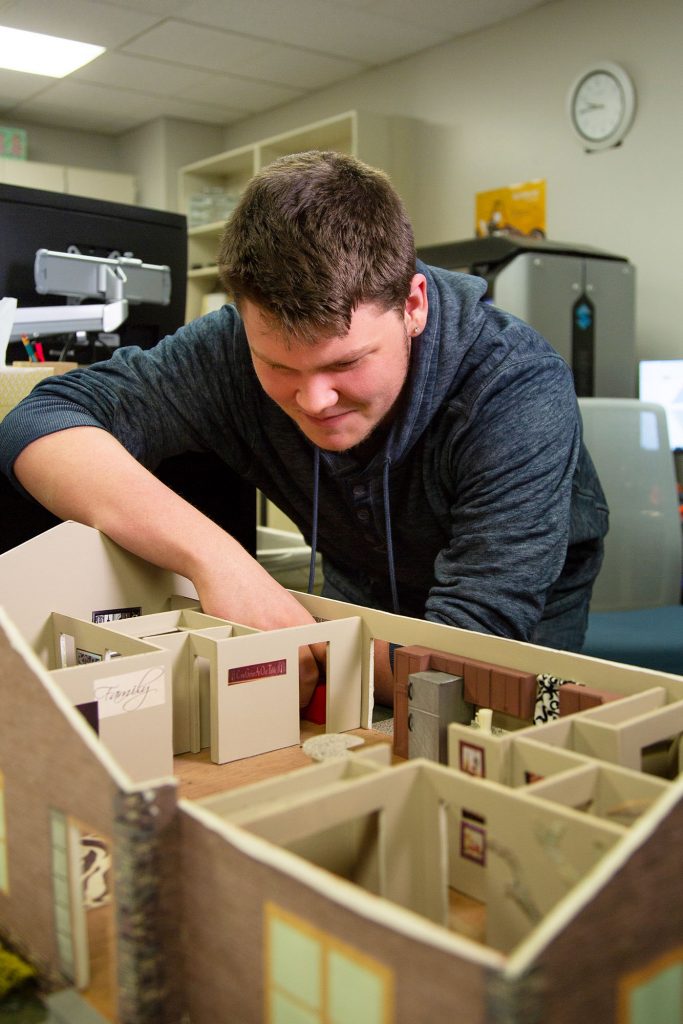 photo of a drafting student looking at a house model