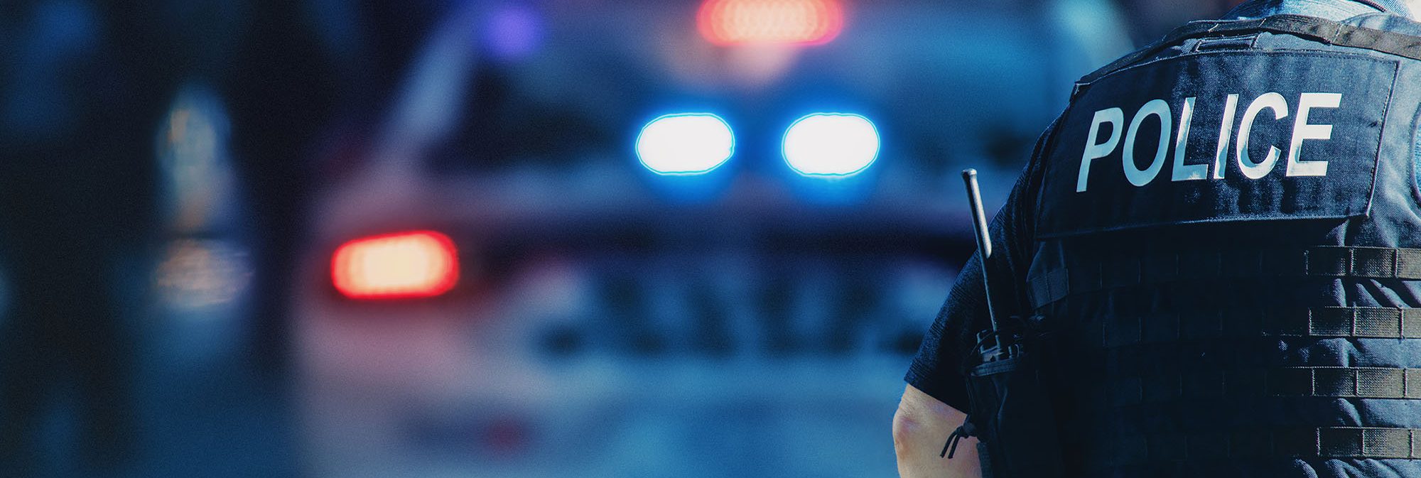 picture of a police officer near a cop car with lights on