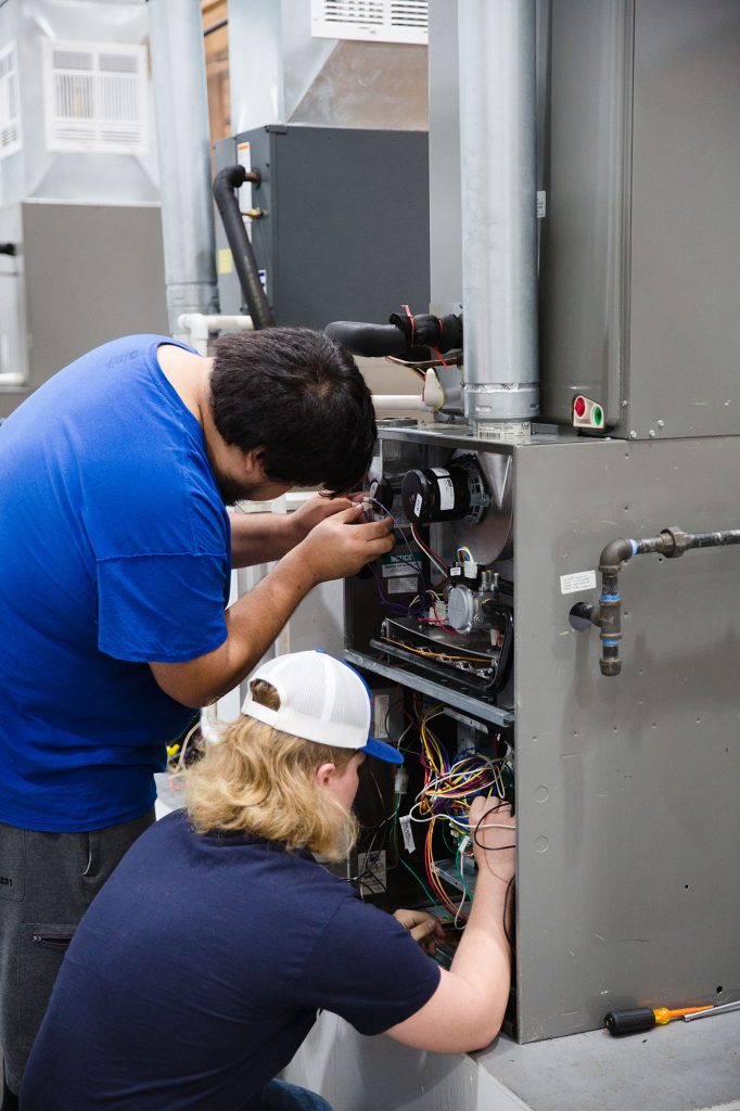 two Central Tech HVAC students working on a unit