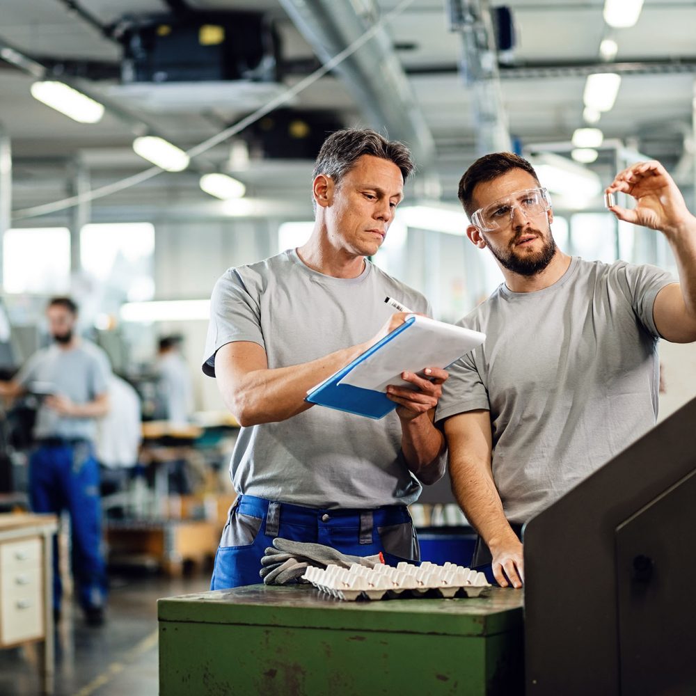 two men talking on a manufacturing floor